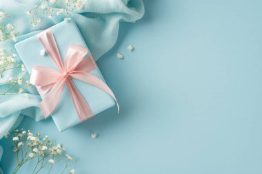 Zarif çiçekler ve kumaşlarla çevrili pembe bir kurdeleyle süslenmiş büyüleyici pastel hediye kutusu.