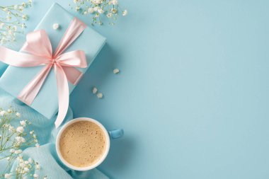 Pastel mavisi bir kahve fincanı, kurdeleli bir hediye ve narin çiçekler.