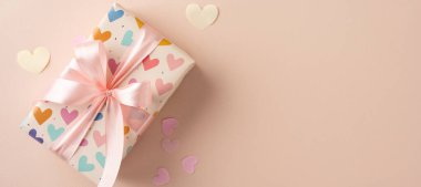 Renkli bir kalp desenine sarılı, saten kurdeleli güzel bir hediye kutusu. Aşkı, kutlamaları ve özel durumları ifade etmek için uygun. Sevgililer Günü, Anneler Günü, doğum günleri için harika.