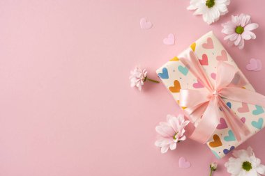 Çiçeklerin arasına pembe bir kurdele yerleştirilmiş dekoratif bir hediye.