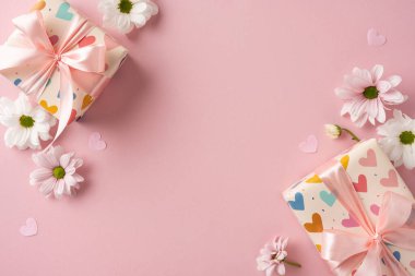 Arkaplanda pembe kurdeleler ve papatyalar olan hediye kutuları kutlamayı ve aşkı çağrıştırıyor.