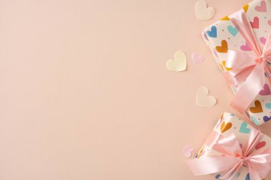 Yumuşak pembe arka planda kalp süslemeleri ve kurdelelerle renklendirilmiş hediyeler. Yıldönümleri, Sevgililer Günü ya da Anneler Günü gibi kutlamalar için mükemmel bir ortam.