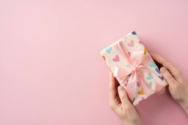 Kalp desenli kağıda sarılı harika bir hediye ve pembe arka planda kurdele kutlama temalı kavramlar için ideal hale getiriyor.