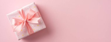 Pembe kağıda sarılı zarif hediye kutusu ve pembeye yerleştirilmiş fiyonk.