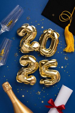 Mezuniyet konseptinde 2025 yazılan altın balonlar, şampanya, diploma ve dikey mavi arkaplan
