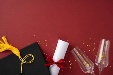 Mezuniyet şapkasının düz kompozisyonu, yuvarlanmış diploma ve kırmızı arka planda parlak süslemeler.