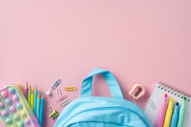 Pastel okul sırt çantası ve renkli kırtasiye malzemelerinin düzgünce düzenlenmiş düz konumu