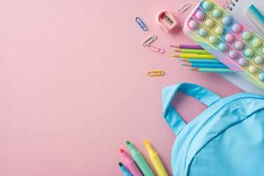 Pastel bir sırt çantası, kalemler ve kırtasiye malzemesi de dahil olmak üzere çok çeşitli eğitim araçları. Okula dönüş projeleri ya da eğitim temaları, sergi organizasyonu ve ilham için mükemmel.