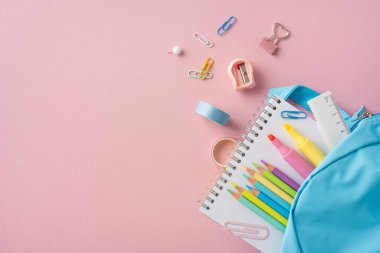 Pastel kırtasiye malzemelerinin ve mavi bir sırt çantasının yer aldığı yaratıcı bir okul malzemesi.