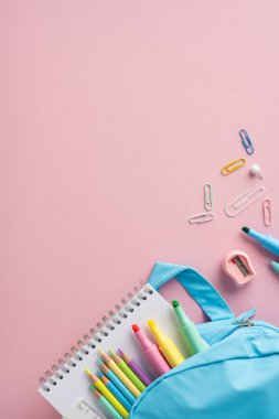 Pastel renkli dikey okul aksesuarları mavi bir kalem çantası ve defter kompozisyonu.