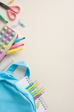 Masanın üzerine renkli malzemelerle dolu mavi sırt çantasıyla okula geri dön.