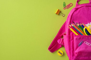 Pembe bir sırt çantası, kalemler ve parlak yüzey üzerine ataç içeren renkli okul malzemeleri.