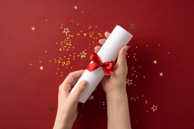 Parlak yıldızlarla çevrili kırmızı bir arka planda canlı kırmızı bir kurdeleyle bağlanmış dekoratif bir parşömen.