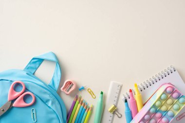 Okula dönüş için hazırlanan sırt çantası, kalem, keçeli kalem ve defter de dahil olmak üzere renkli okul malzemeleri.