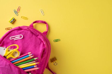 Kalemler, makas ve ataç gibi parlak sarı arkaplanda kırtasiye malzemelerini içeren pembe sırt çantası.