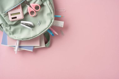 Öğrenmeyi sembolize eden pembe bir yüzeye dağılmış bir sırt çantası ve kırtasiye malzemesi de dahil olmak üzere okul malzemeleri