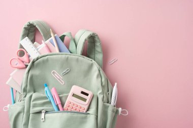Sırt çantasından çıkan kalem, cetvel ve makas içeren düzgün bir kırtasiye düzeni
