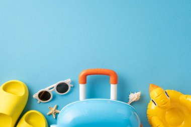 Renkli bir bavul, güneş gözlüğü ve plaj eşyaları da dahil olmak üzere parlak yaz temalı seyahat gereksinimleri