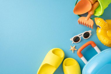 Parlak sahil ve seyahat malzemeleri, yaz tatillerini sembolize eden mavi bir arka plana yaratıcı bir şekilde yerleştirilmiş.
