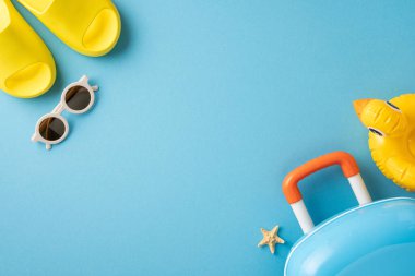 Bir bavul, güneş gözlüğü, sandalet ve şişirilebilir de dahil olmak üzere seyahat için gerekli malzemeler. Sahne yaz tatillerini, güneş ışığını ve plaj rahatlığını çağrıştırıyor.