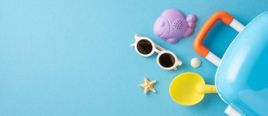 Yaz plajı eşyaları, güneş gözlüğü ve mavi arka planda oyuncaklar da dahil olmak üzere seyahat gereksinimleri düz yatar, rahatlama, tatil ve boş zaman temaları çağrıştırır