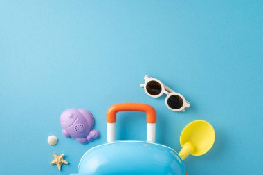 Oyuncak bavul, güneş gözlüğü ve plaj oyuncakları içeren renkli yaz temalı eşyalar.
