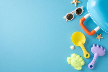 Mavi bir yüzeye yerleştirilmiş canlı plaj oyuncakları ve yaz için gerekli şeyler.
