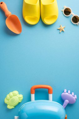 Tatil ya da tatil teması olarak mavi bir yüzeye yerleştirilmiş ayakkabılar, güneş gözlükleri, oyuncaklar ve bavullar da dahil olmak üzere yaz plajı esaslarının düz bir bileşimi yatıyordu.