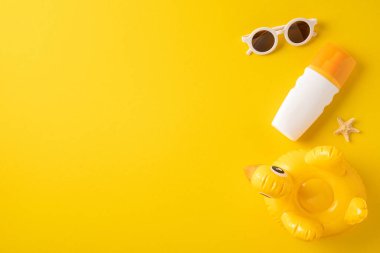 Güneş gözlüğü, güneş kremi şişesi, şişirilebilir ördek yüzeyi ve sarı üzerine deniz yıldızı.
