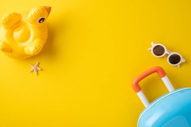 Yaz seyahatlerinde kullanılan parlak sarı arka planda bavul, güneş gözlüğü, şişirilebilir şamandıra ve rahatlama ve tatilleri çağrıştıran bir denizyıldızı yer alıyor.