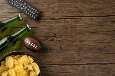Bira şişeleri, patates cipsi, futbol topu ve tahta bir masanın üzerindeki uzaktan kumanda rahatlatıcı ve çekici bir atmosfer yaratır. Boş zamanları, oyun günlerini ve gündelik anları resmetmek için idealdir