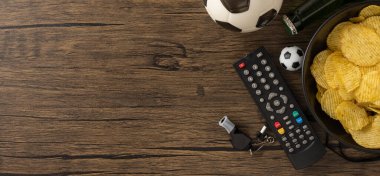 Futbol temalı ahşap masa, abur cuburlar, bira ve oyun zamanı için gerekli eğlence malzemeleri.