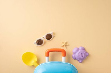 Bavul, oyuncak, güneş gözlüğü ve deniz yıldızı da dahil olmak üzere yaz seyahati eşyalarının en üst görüntüsü, bayram atmosferini çağrıştırıyor.