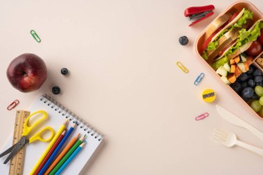 Masasında meyve ve okul malzemeleri olan sağlıklı beslenme çantası dengeli yaşam tarzını ve öğrenmeyi teşvik ediyor.