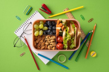 Sağlıklı beslenme çantası renkli okul malzemeleriyle çevrili çeşitli atıştırmalıklarla dolu..