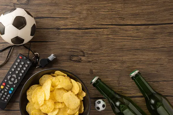 Ahşap bir yüzeydeki eşyalar evdeki rahat bir futbol maçını temsil ediyor.