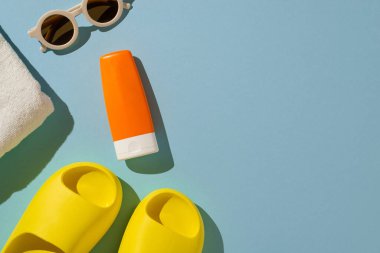 Renkli arka planda güneş kremi, güneş gözlüğü, havlu ve sandaletler içeren canlı bir yaz dairesi.