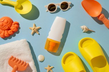 Pastel arka planda, güneş kremi, güneş gözlüğü ve plaj oyuncakları da dahil olmak üzere çeşitli yaz eşyaları düzenlendi.