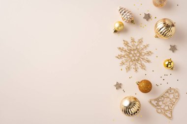 Festivalden ilham almak için bej bir yüzeye yerleştirilmiş altın süsler ve mevsimlik dekorasyonlar