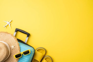 Seyahat gereksinimleri arasında bavul, hasır şapka, güneş gözlüğü ve sarı bir zemin üzerinde sandaletler, somutlaştırıcı tatil titreşimleri var. Uçak ve denizyıldızı yaz seyahati ve tropikal noktalara elementler ekler.