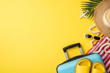 Bavul, şapka, güneş gözlüğü ve sarı arka plandaki uçak da dahil olmak üzere yaz tatili malzemeleri.