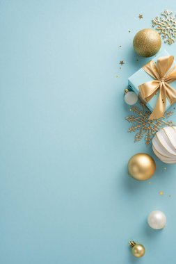 Altın süsler, hediye kutuları ve yıldızların mavi arka planda durduğu, mevsimsel ve zarif bir atmosfer yaratan düz, dikey bir Noel düzeneği.