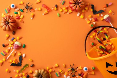 Cadılar Bayramı temalı turuncu bir yüzey üzerinde balkabağı ve örümceklerin yer aldığı şeker ve süslemeler.