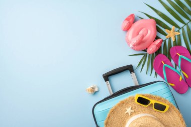 Açık mavi arka planda bir valiz, hasır şapka, güneş gözlüğü ve plaj eşyalarının yer aldığı beste yaz tatili ve seyahat temalarını gözler önüne seriyor.