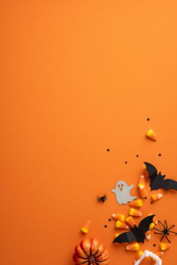 Cadılar Bayramı süslemeleri, mısır şekeri ve turuncu arka planda bir balkabağı içeren düz bir ekran. Bayram sezonunu kutlamak ve şenlik havası vermek için mükemmel.