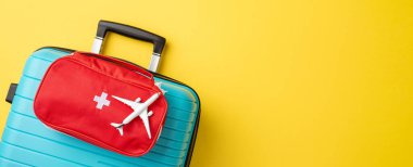 Seyahat gereksinimleri mavi bavul ve kırmızı ilk yardım çantasıyla temsil ediliyor.