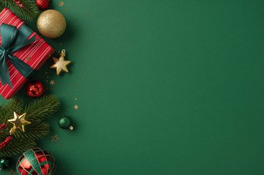 Yeşil bir arkaplana karşı paketlenmiş hediye, süsler ve yeşillik içeren şenlikli Noel düzlüğü