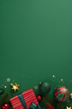 Noel süsleri, sarılı bir hediye, köknar dalları ve altın yıldızlar da dahil olmak üzere dikey süslemeler yeşil bir yüzeye bayram neşesini çağrıştırıyor