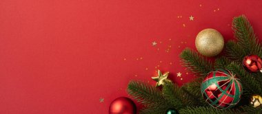 Kıpkırmızı arka planda her zaman yeşil dalları olan renkli Noel süslerinin yer aldığı zarif bir kompozisyon. Bayram temaları ve mevsimsel kutlamalar için mükemmel.