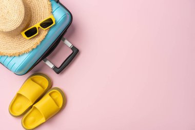 Mavi bavullu, hasır şapkalı, sarı slaytlı ve güneş gözlüklü şık bir yaz seyahati. Tatil planlaması için ideal